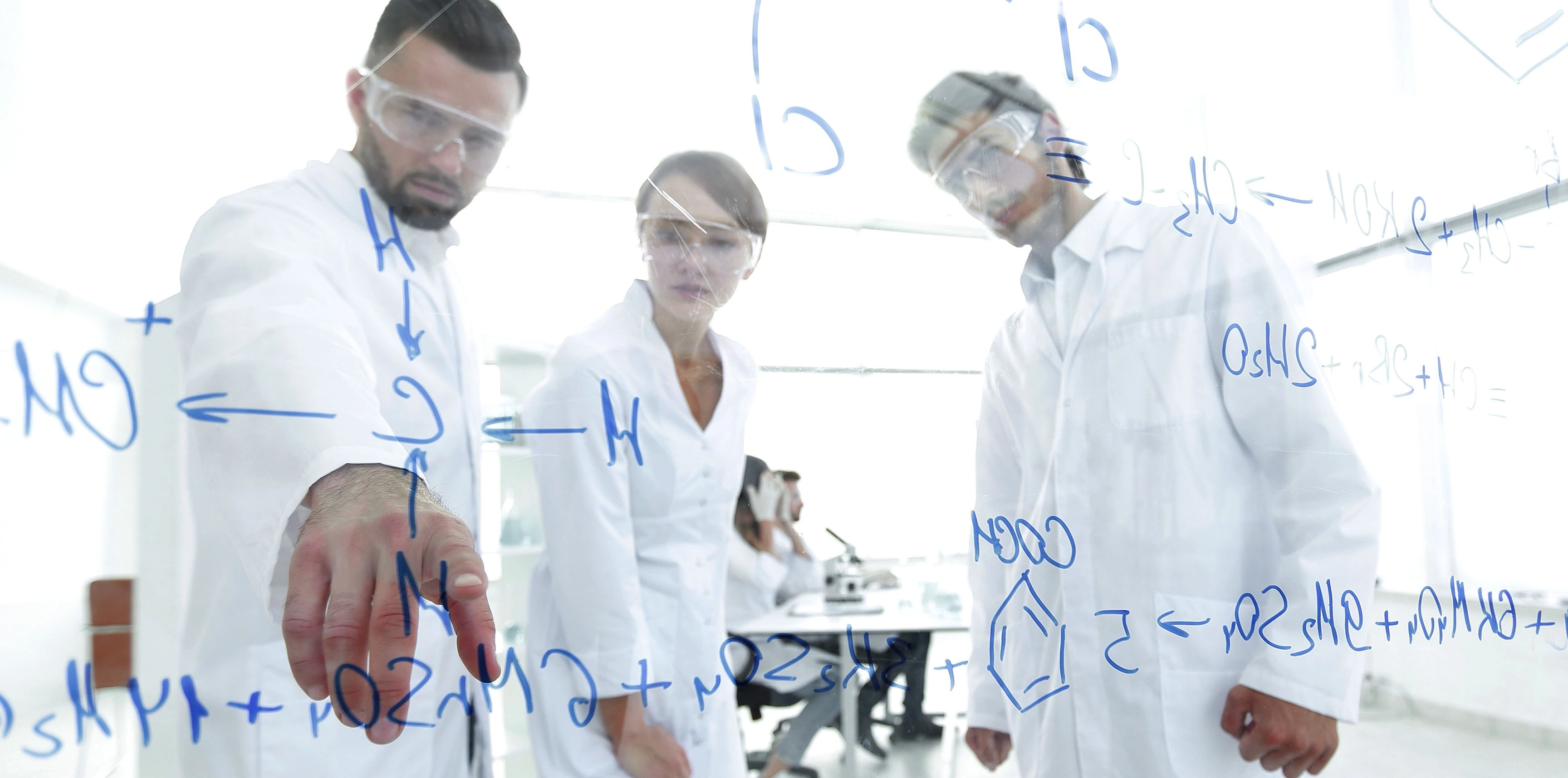 Scientests wearing PPE looking at equations