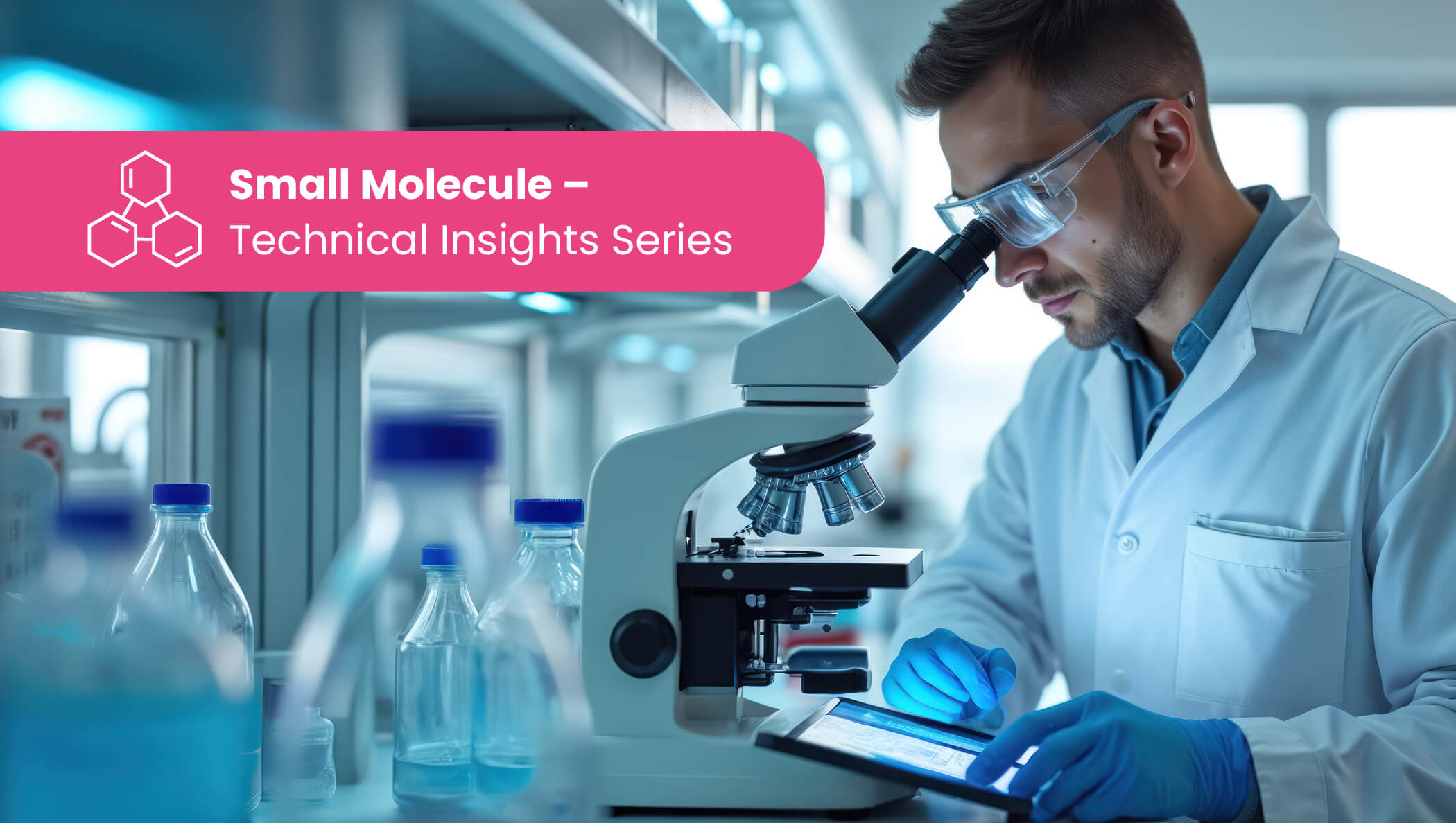 Scientist wearing safety gear uses a microscope and tablet at a busy lab bench with bottles and instruments.