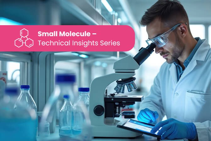 Scientist wearing safety gear uses a microscope and tablet at a busy lab bench with bottles and instruments.